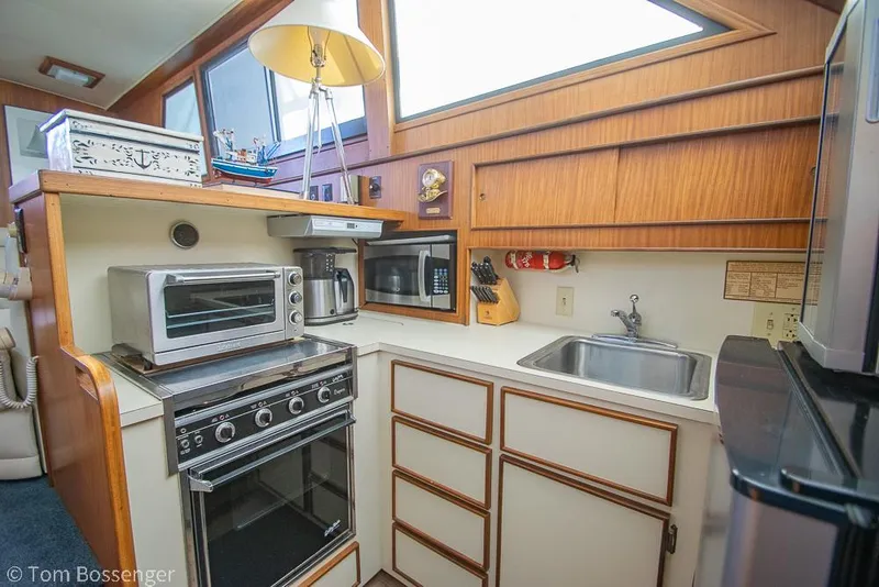 Slide: The Image of 1986 Hatteras 43 Motor Yacht kitchen with appliances, sink, and wooden cabinetry. - 20