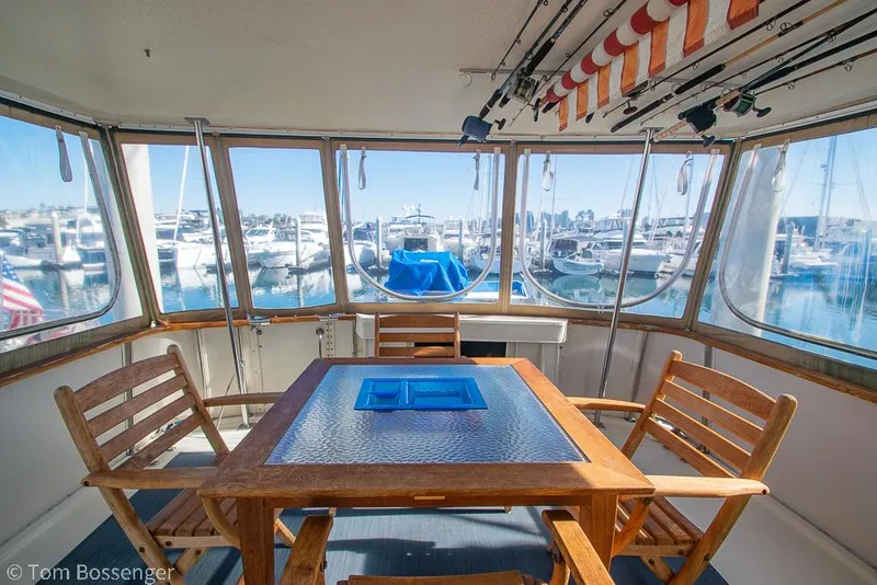 Slide: The Image of 1986 Hatteras 43 Motor Yacht interior with wooden table, chairs, and marina view. - 35