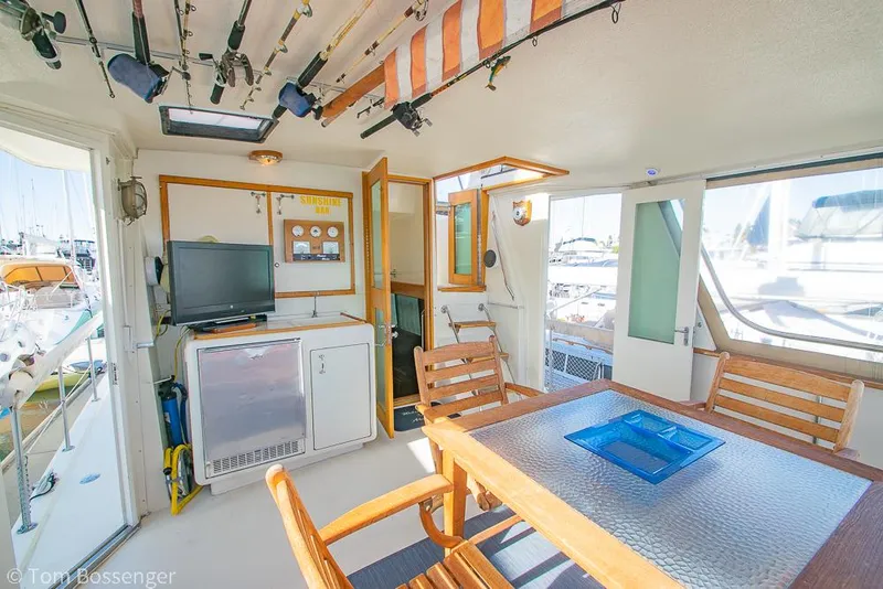 Slide: The Image of 1986 Hatteras 43 Motor Yacht interior with dining area, fishing rods, and marina view. - 36