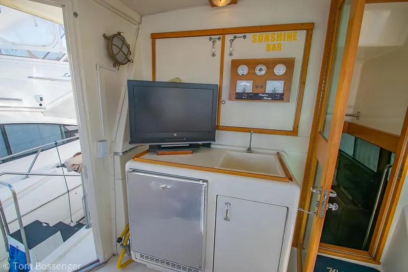 Slide: The Image of 1986 Hatteras 43 Motor Yacht interior with TV, fridge, and "Sunshine Bar" panel. - 37