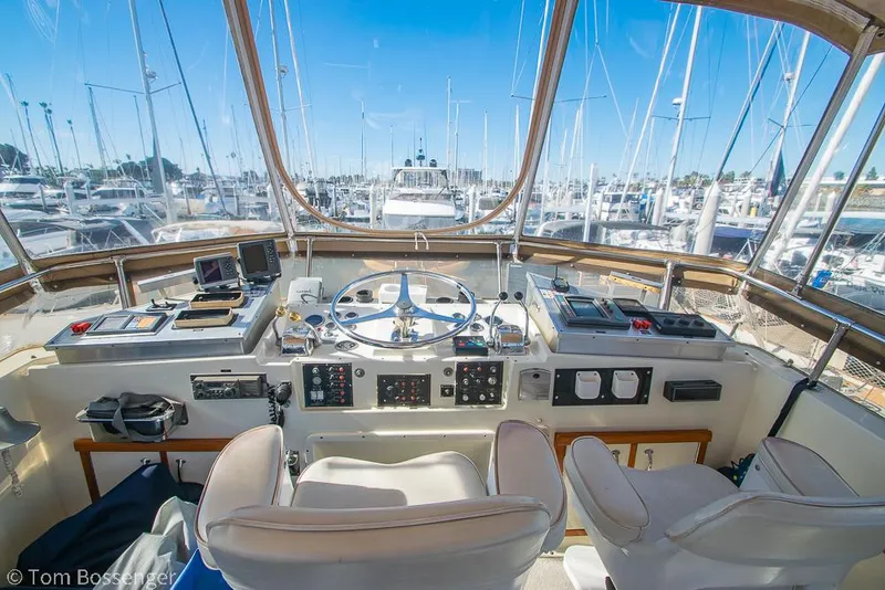 Slide: The Image of 1986 Hatteras 43 Motor Yacht helm with marina view, featuring navigation equipment and controls. - 42