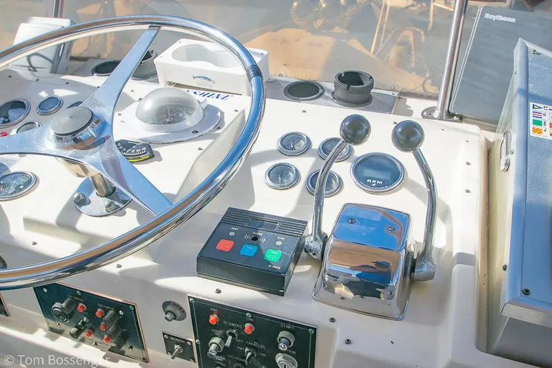 Slide: The Image of Control panel of a 1986 Hatteras 43 Motor Yacht with steering wheel and throttle levers. - 44