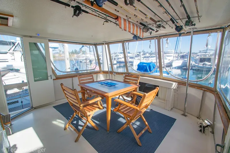Slide: The Image of 1986 Hatteras 43 Motor Yacht interior with wooden table, chairs, and fishing rods. - 6