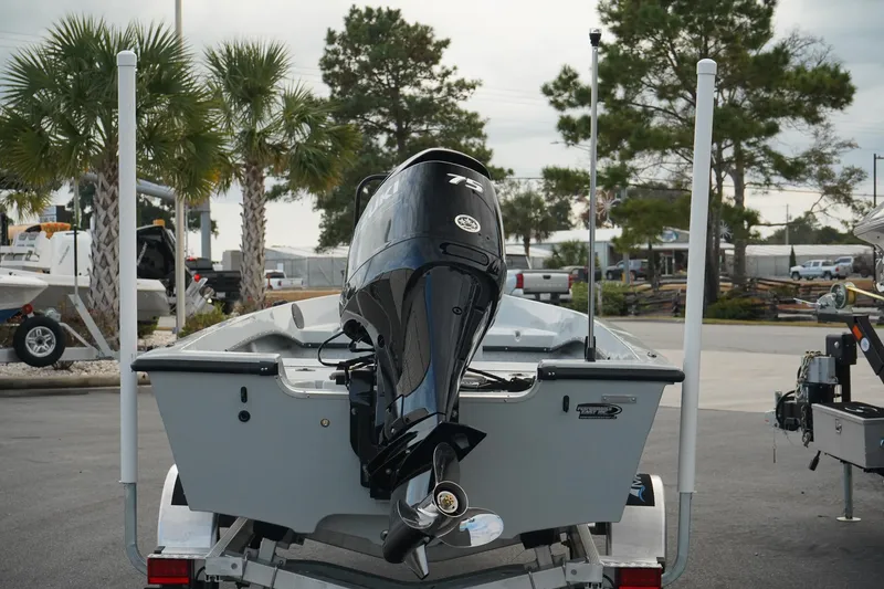 Slide: The Image of 2025 Mi Tide V1602 boat with outboard motor on trailer, parked near palm trees. - 3