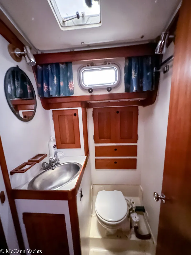 Slide: The Image of 1988 Bristol 41.1 Aft Cockpit yacht bathroom with sink, toilet, and wooden cabinetry. - 36