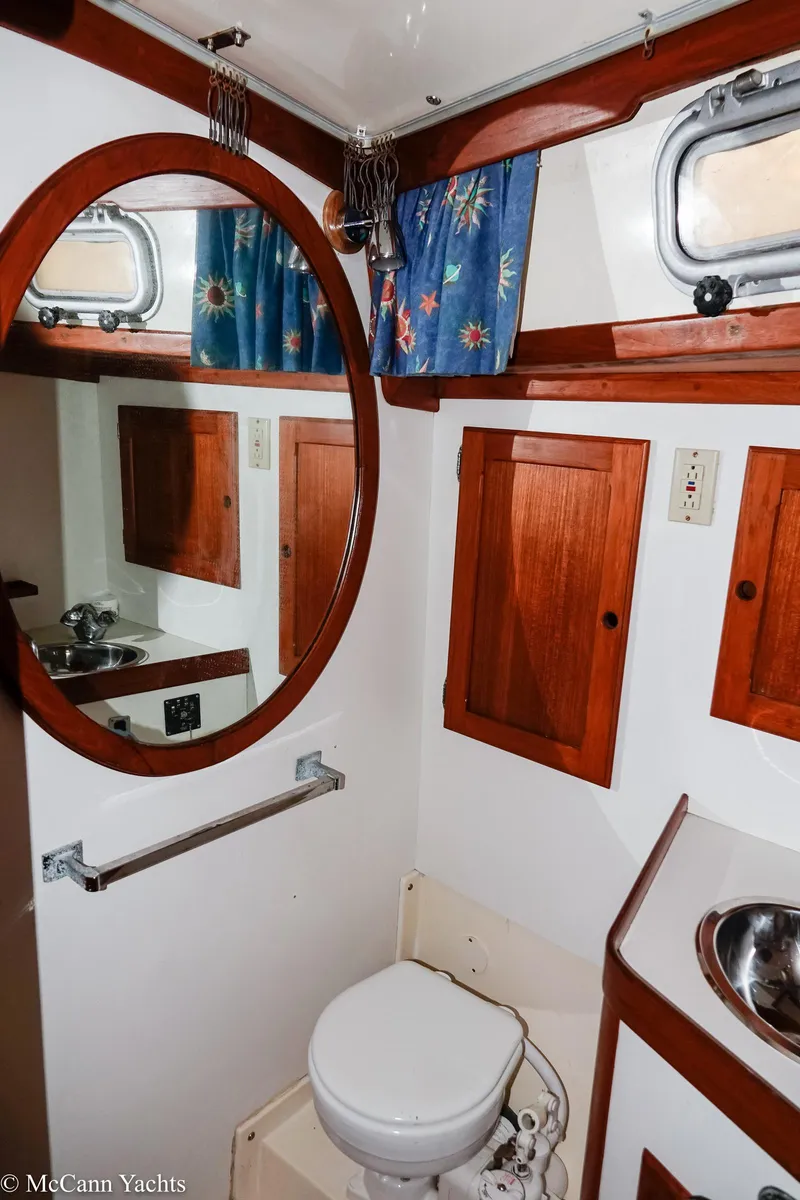 Slide: The Image of 1988 Bristol 41.1 Aft Cockpit yacht bathroom with wooden cabinets and round mirror. - 41