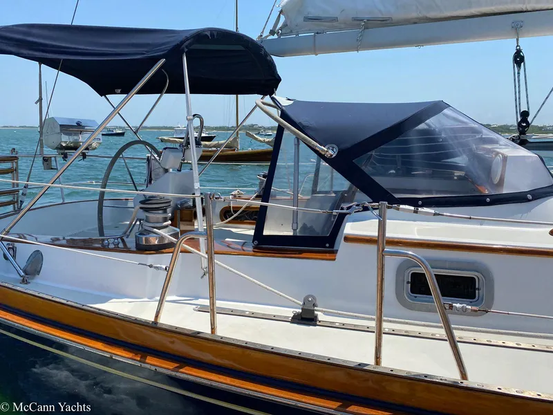Slide: The Image of 1988 Bristol 41.1 Aft Cockpit sailboat with blue canopy, docked in a serene marina. - 6