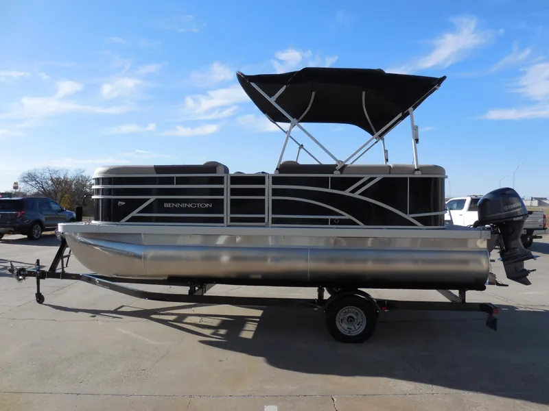 Slide: The Image of 2025 Bennington 188 SL pontoon boat on trailer, under clear blue sky. - 4