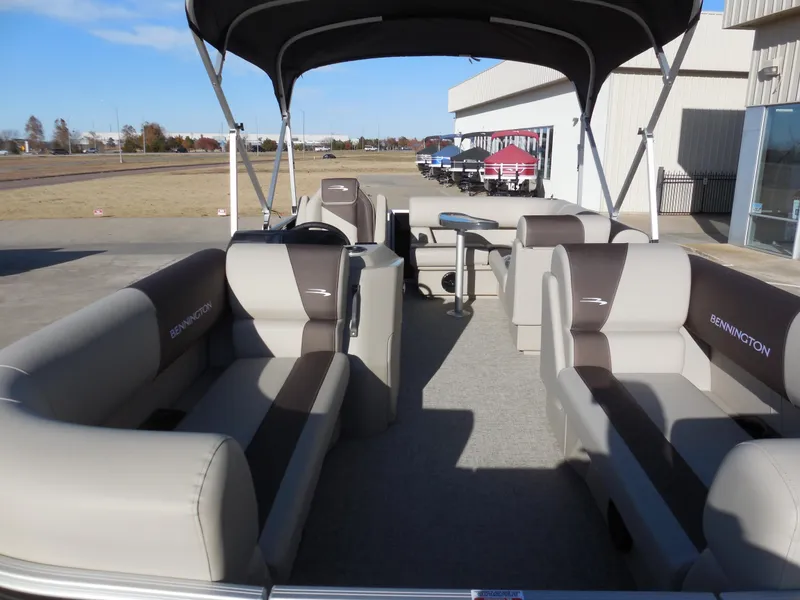 Slide: The Image of 2025 Bennington 188 SL pontoon boat with spacious seating and canopy, parked outdoors. - 5