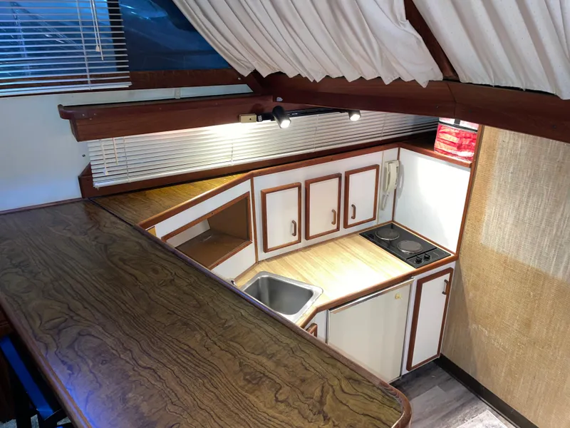 Slide: The Image of 1989 Marinette 41 Marquis Convertible yacht kitchen with wood accents and compact design. - 16