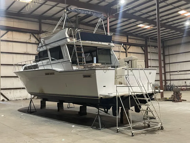 Slide: The Image of 1989 Marinette 41 Marquis Convertible boat in warehouse, elevated on stands. - 2