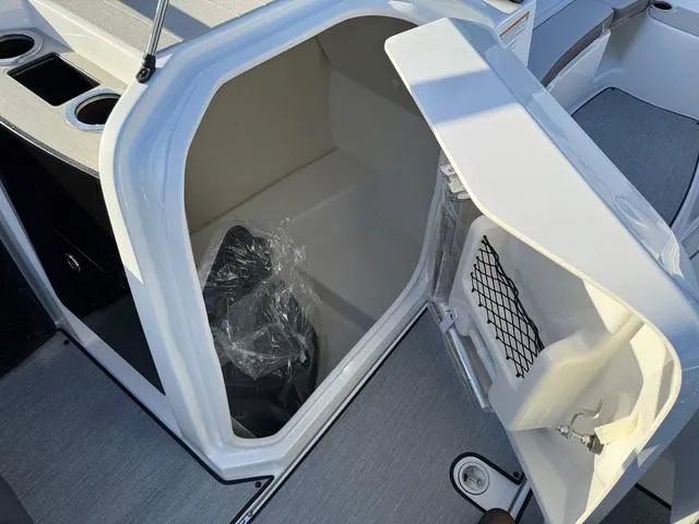 Slide: The Image of 2025 Yamaha AR250 boat storage compartment with open door and cup holders. - 15