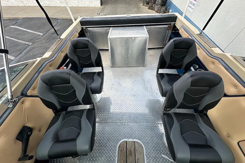 Slide: The Image of 1987 Seaswirl Sierra II boat interior with four black seats and metal flooring. - 17