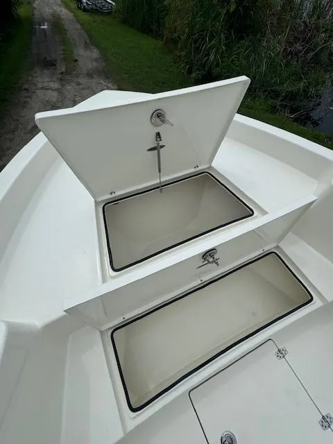Slide: The Image of 2025 Pathfinder 2700 Open boat storage compartments, open lids, white interior, outdoor setting. - 17