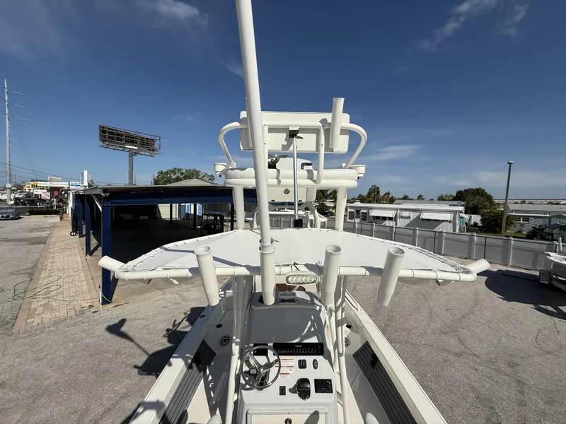 Slide: The Image of 2025 Pathfinder 2600 TRS boat with T-top and rod holders, parked outdoors under clear sky. - 10