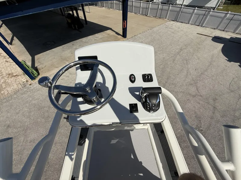 Slide: The Image of 2025 Pathfinder 2600 TRS boat helm with steering wheel and controls, docked outdoors. - 24