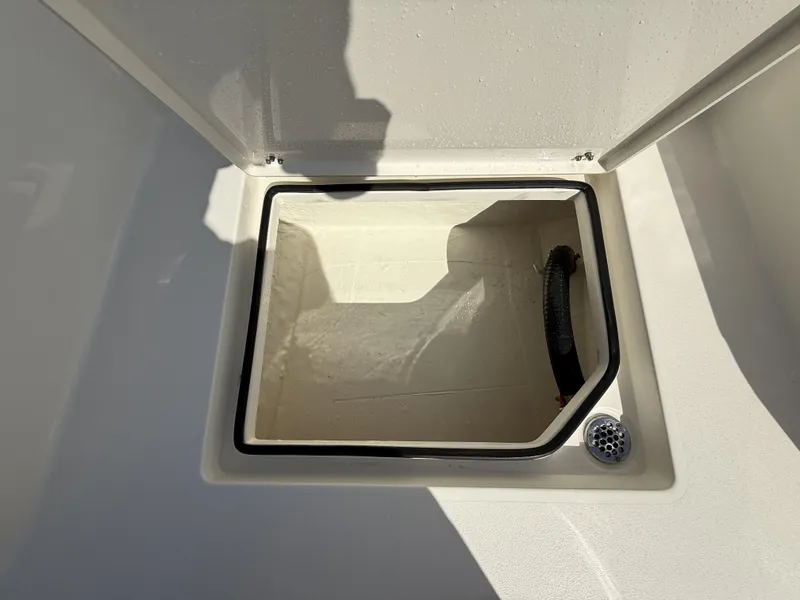 Slide: The Image of Open storage compartment on 2025 Pathfinder 2600 TRS boat, featuring a drain and hose. - 47