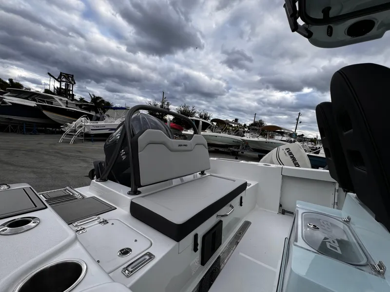 Slide: The Image of 2025 Sea Pro 245 FLX boat interior with seating and storage, under cloudy skies. - 34