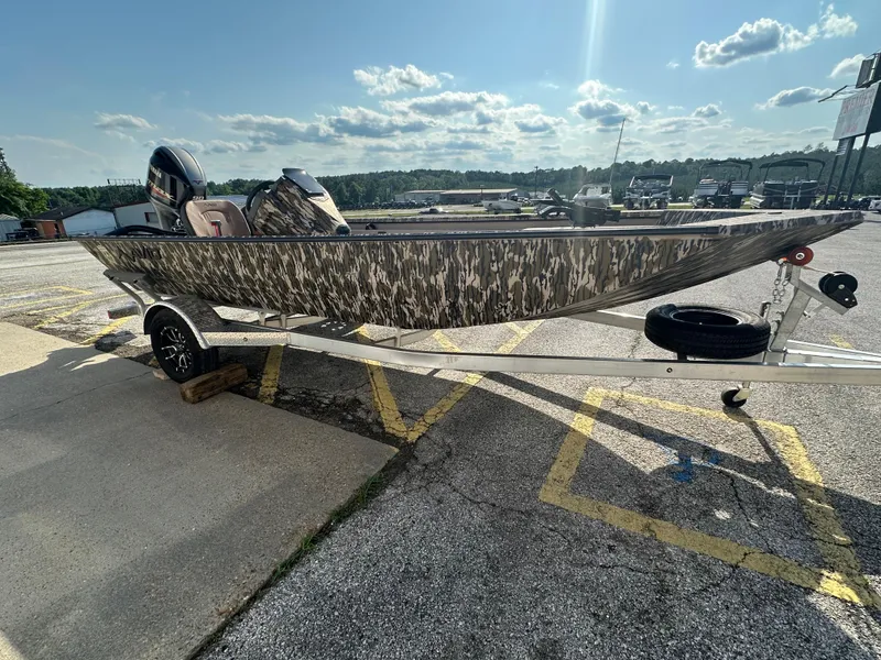 Slide: The Image of 2024 Avid 18SC Rogue boat with camouflage design on a trailer in a parking lot. - 5