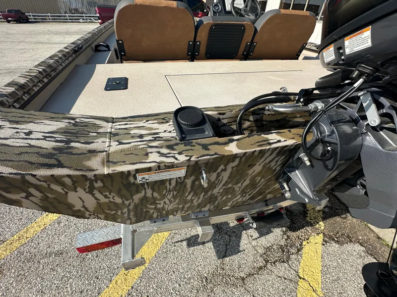Slide: The Image of 2024 Avid 18SC Rogue boat with camouflage design and motor, parked on a trailer. - 9