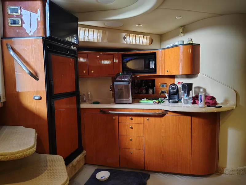 Slide: The Image of 2001 Sea Ray Sundancer yacht kitchen with wooden cabinets, appliances, and stairs. - 14