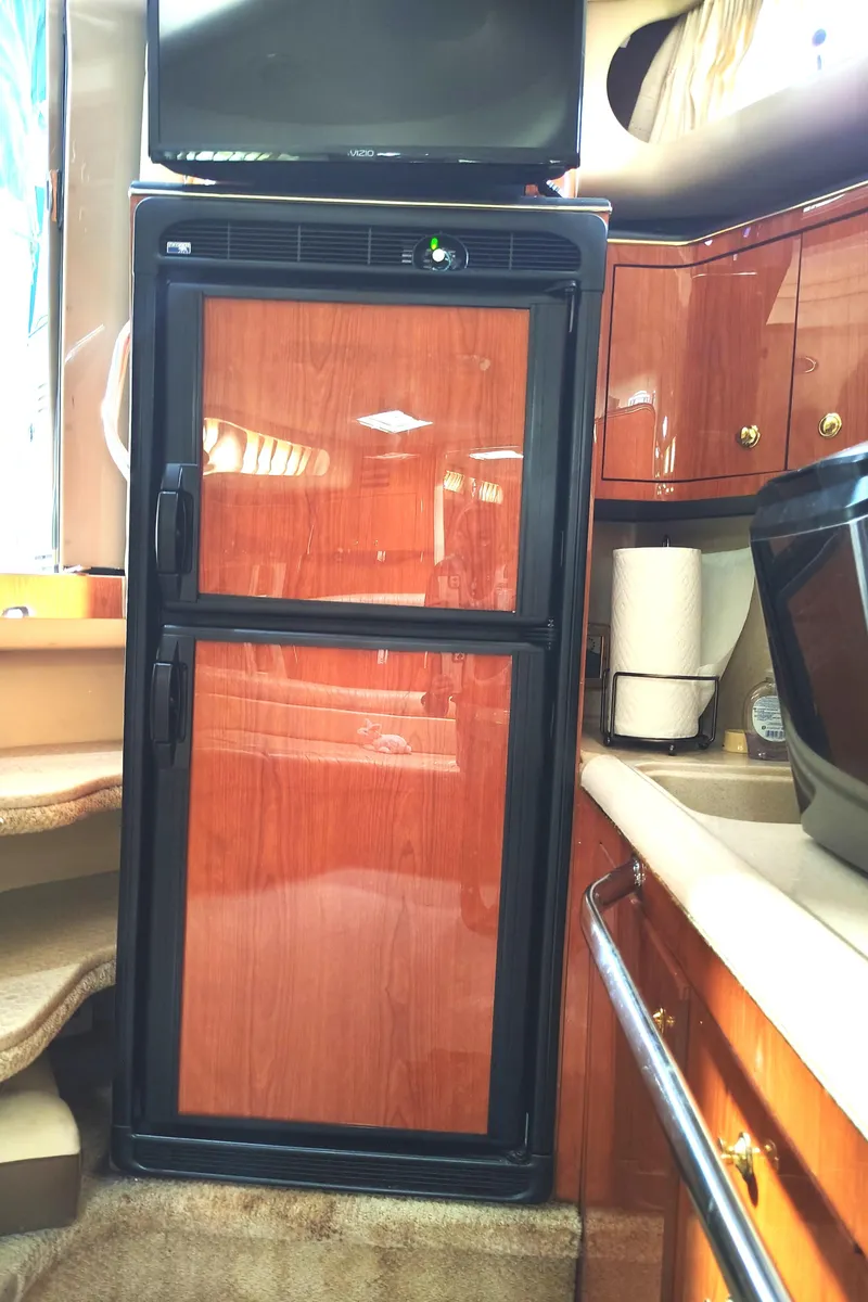 Slide: The Image of 2001 Sea Ray Sundancer interior with wood-paneled fridge and modern amenities. - 31