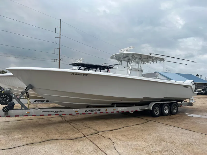 Slide: The Image of 2021 Contender 39 ST boat on trailer, parked outdoors under cloudy sky. - 1