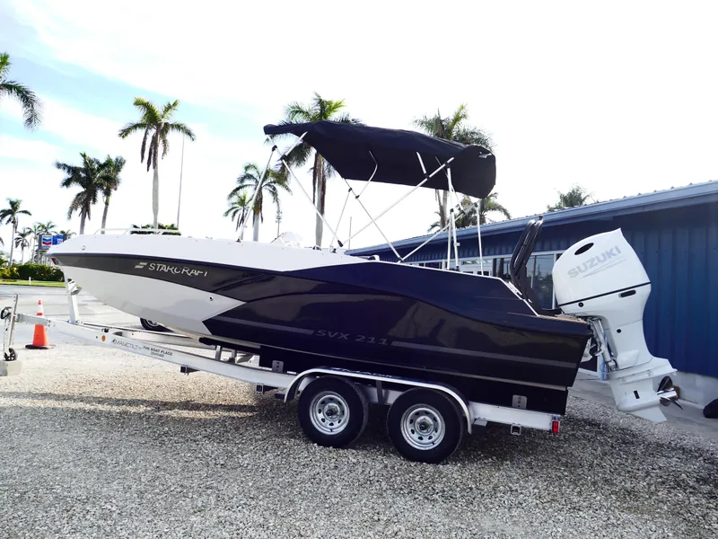 Slide: The Image of 2025 Starcraft SVX 211 OB boat on trailer with Suzuki outboard motor, parked outdoors. - 0