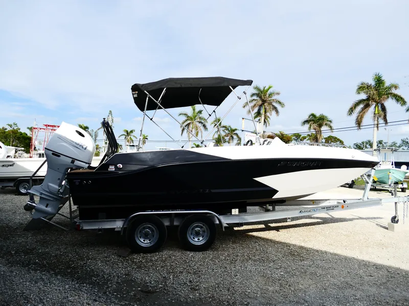 Slide: The Image of 2025 Starcraft SVX 211 OB boat on trailer, black and white design, palm trees in background. - 2
