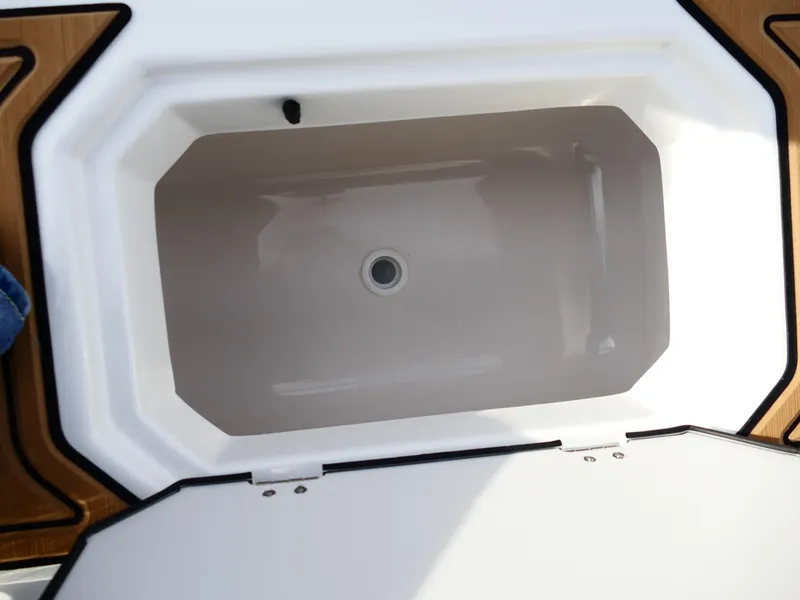 Slide: The Image of Starcraft SVX 211 OB 2025 boat storage compartment, open lid, white interior. - 37