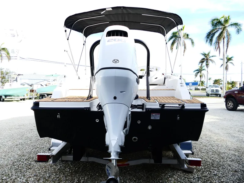 Slide: The Image of 2025 Starcraft SVX 211 OB boat with outboard motor, parked on trailer, palm trees in background. - 6