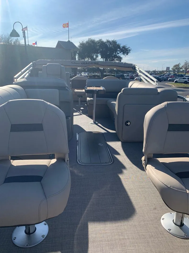 Slide: The Image of 2025 Sun Tracker Fishin' Barge 22 XP3 interior with beige seating and steering console. - 2