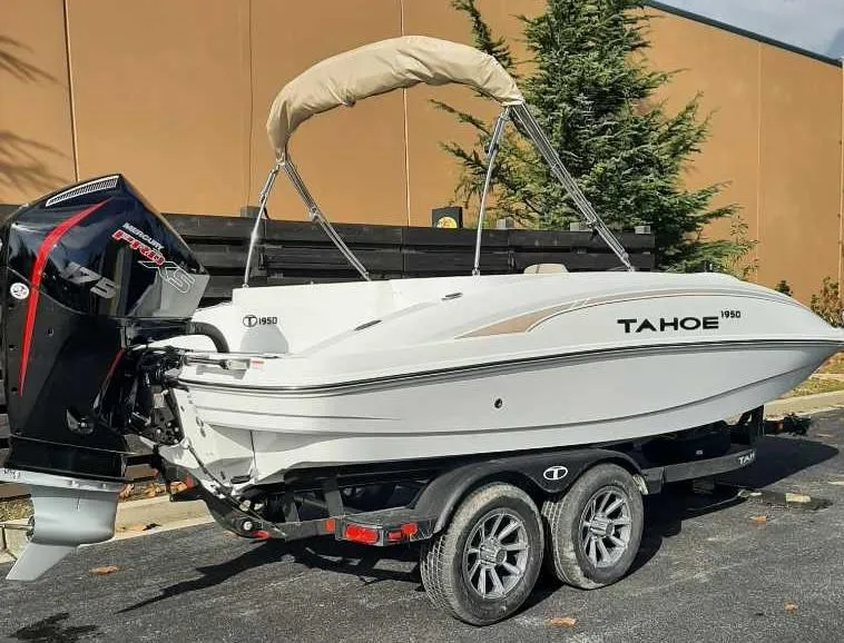Slide: The Image of 2025 Tahoe 1950 boat on trailer with outboard motor, parked outdoors. - 1
