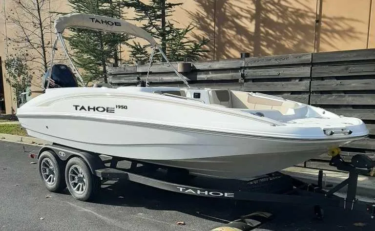 Slide: The Image of 2025 Tahoe 1950 boat on trailer, parked outdoors. - 2
