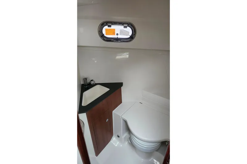 Slide: The Image of 2025 Pursuit OS 325 Offshore boat bathroom with sink, toilet, and porthole window. - 31
