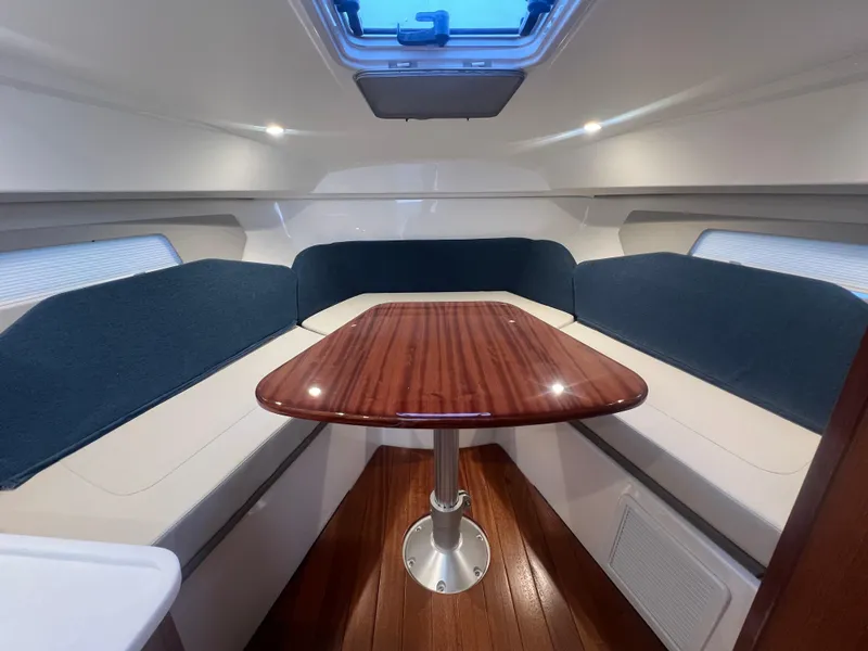 Slide: The Image of 2025 Pursuit OS 325 Offshore cabin with elegant wood table and blue cushioned seating. - 46