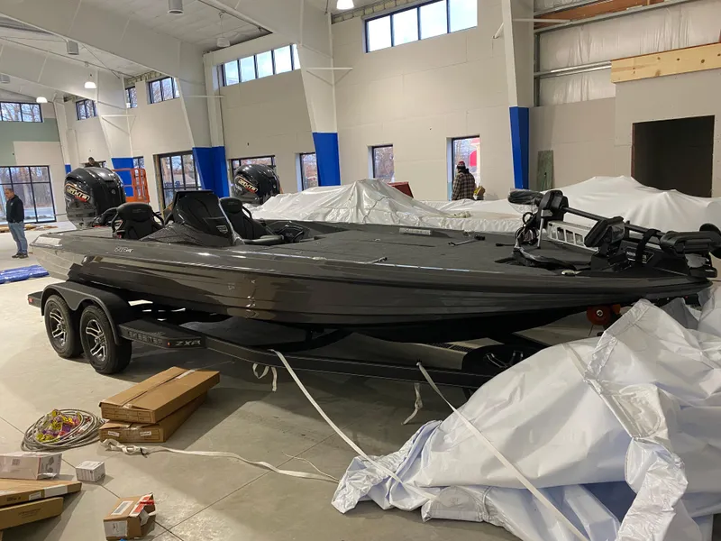 The Image of 2025 Skeeter ZXR21 boat in showroom, sleek design, dual motors, on trailer. - 1