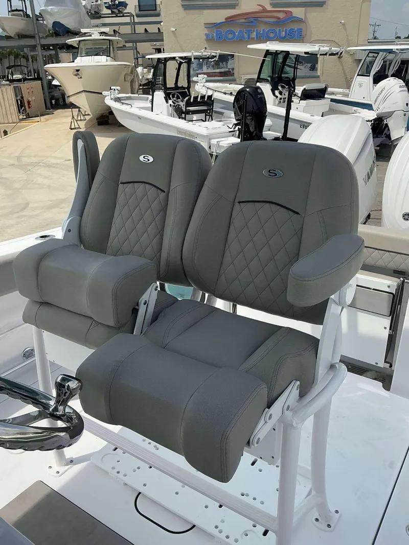 Slide: The Image of 2025 Sportsman 252 Open boat seats with gray upholstery at a marina. - 15