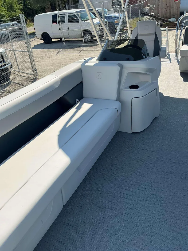 Slide: The Image of 2025 Sweetwater 2286 CSE boat interior with seating and console, parked outdoors. - 7