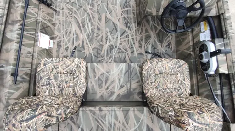 Slide: The Image of 2025 Lowe Roughneck RX1860 SC boat interior with camouflage seats and steering console. - 5
