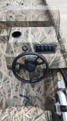 Slide: The Image of 2025 Lowe Roughneck RX1860 SC boat console with camouflage design and steering wheel. - 6
