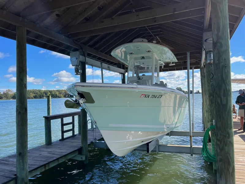 Slide: The Image of 2021 Cobia 240 Center Console boat docked under a wooden shelter. - 2