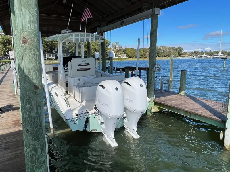 Slide: The Image of 2021 Cobia 240 Center Console boat docked under a wooden shelter. - 3