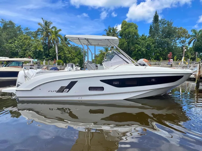 The Image of 2025 Beneteau Flyer 9 SUNdeck boat docked on calm water, surrounded by lush greenery. - 0