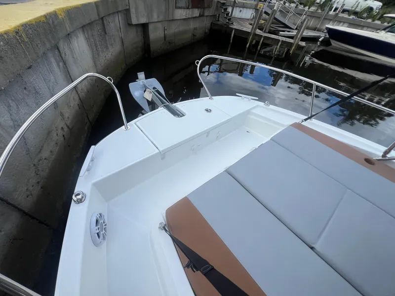 Slide: The Image of 2025 Beneteau Flyer 9 SUNdeck boat with cushioned seating and anchor, docked in marina. - 4