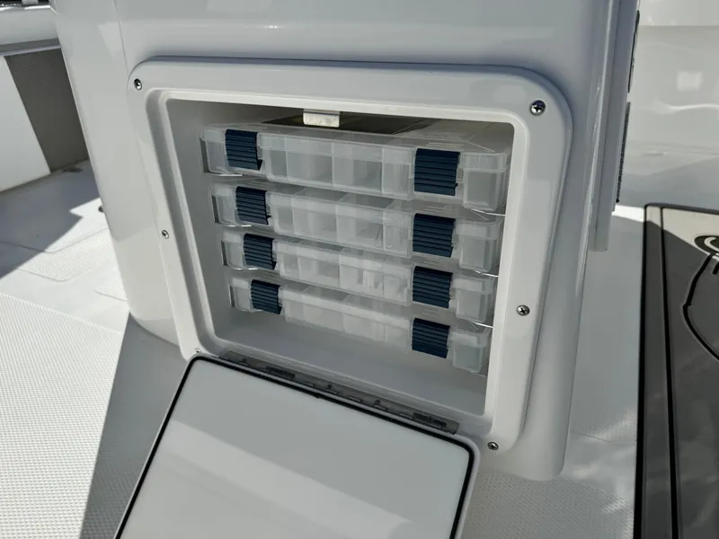 Slide: The Image of Storage compartment on 2025 BlackJack 256 Coastal boat, featuring organized tackle boxes. - 13