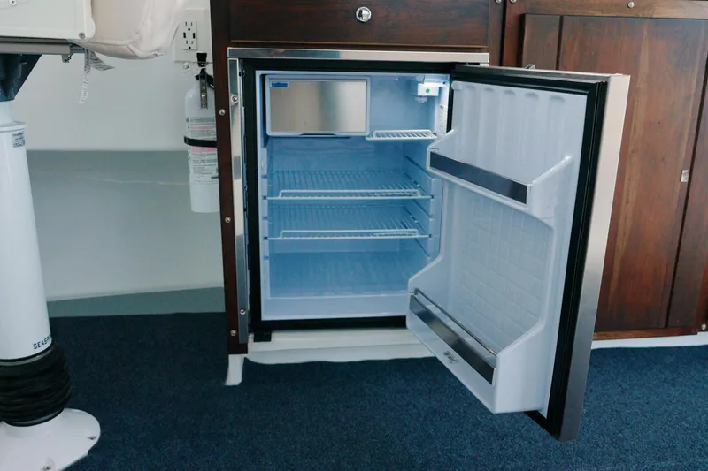 Slide: The Image of Open refrigerator inside 2023 Millennium Marine NuWave 37 boat, showcasing interior shelves. - 16