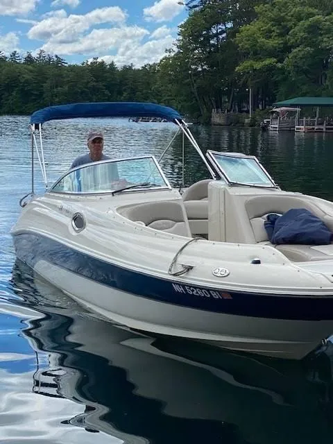 Slide: The Image of 2003 Sea Ray 240 Sundeck boat on a serene lake with lush trees. - 3