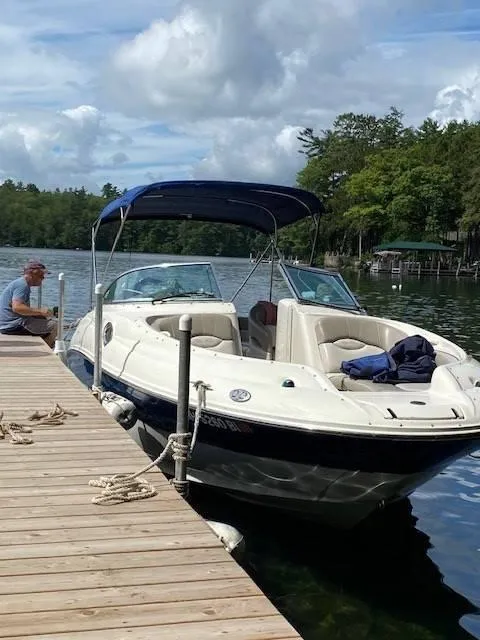 Slide: The Image of 2003 Sea Ray 240 Sundeck docked on a serene lake with lush greenery. - 4
