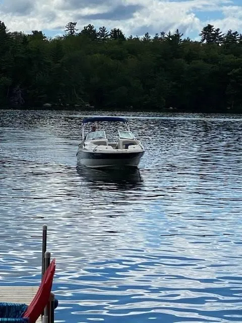 Slide: The Image of 2003 Sea Ray 240 Sundeck on a serene lake with forested background. - 7